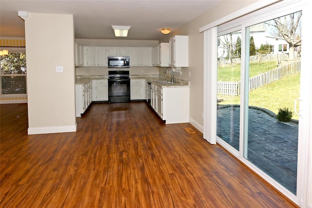 kitchen with dark wood-type flooring, white cabinets, appliances with stainless steel finishes, and a sink