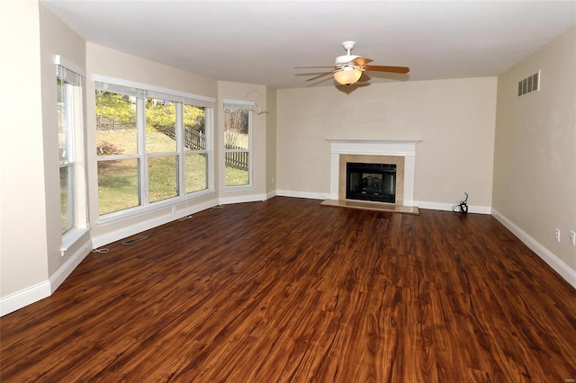 unfurnished living room featuring visible vents, dark wood-type flooring, baseboards, and a glass covered fireplace