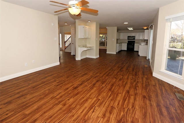 unfurnished living room featuring dark wood-style floors, visible vents, ceiling fan, and baseboards