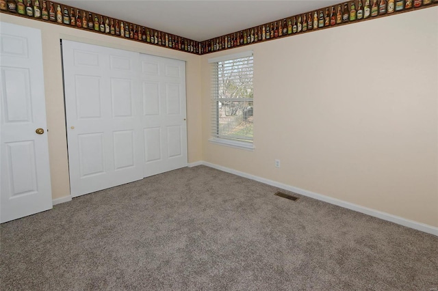 unfurnished bedroom with carpet, visible vents, a closet, and baseboards