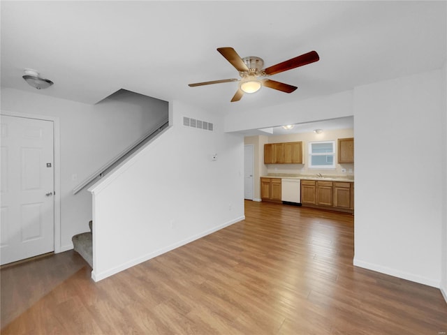 unfurnished living room featuring light wood-type flooring, visible vents, baseboards, and stairs