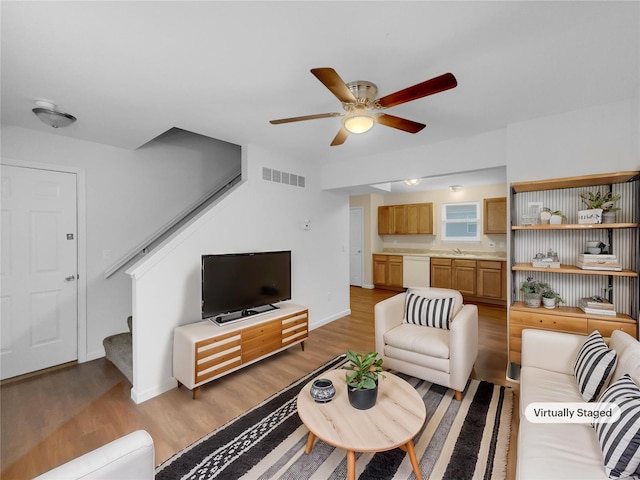 living area featuring visible vents, stairway, a ceiling fan, wood finished floors, and baseboards