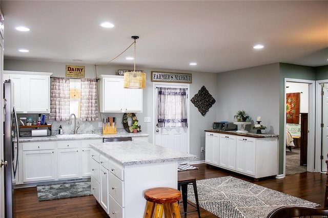 kitchen with hanging light fixtures, a center island, white cabinetry, and sink