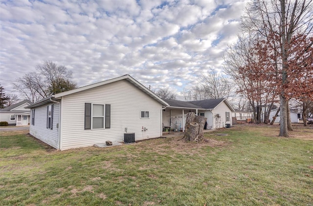 view of side of home featuring a yard and central AC