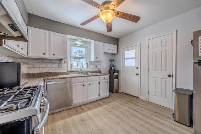 kitchen featuring sink, appliances with stainless steel finishes, white cabinetry, custom exhaust hood, and light wood-type flooring