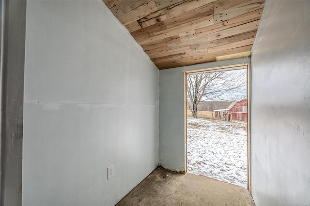 doorway featuring vaulted ceiling, wooden ceiling, and concrete floors