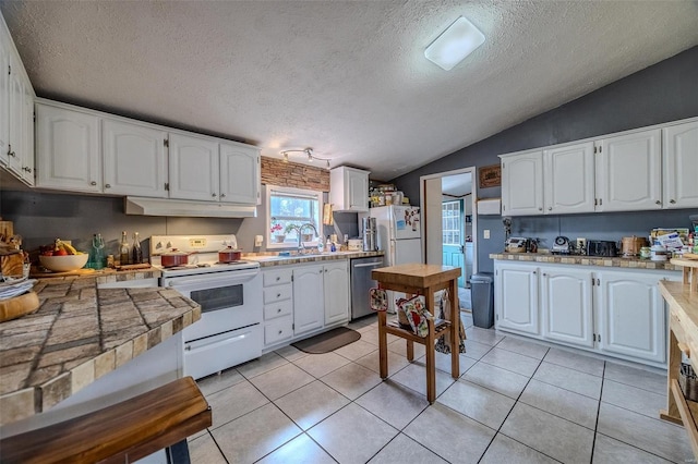 kitchen featuring lofted ceiling, sink, white appliances, light tile patterned floors, and white cabinetry