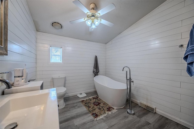 bathroom with lofted ceiling, sink, a bathtub, hardwood / wood-style flooring, and toilet