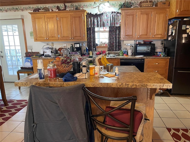 kitchen with a healthy amount of sunlight, light tile patterned floors, a breakfast bar area, and black appliances