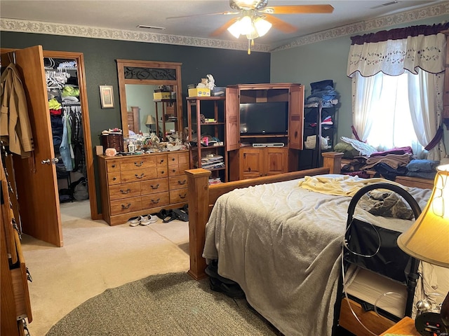 bedroom featuring ceiling fan, a walk in closet, light carpet, and a closet