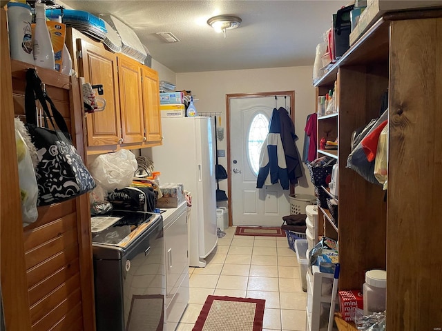 washroom featuring separate washer and dryer, light tile patterned floors, and cabinets