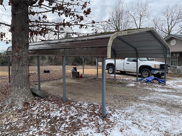 snow covered parking area featuring a carport