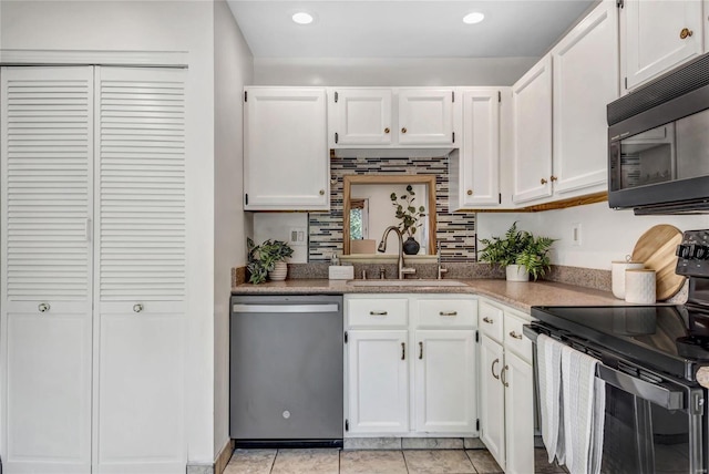 kitchen with white cabinets, a sink, black appliances, and light tile patterned flooring