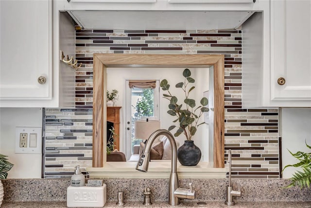 interior details with light stone counters, white cabinets, and tasteful backsplash