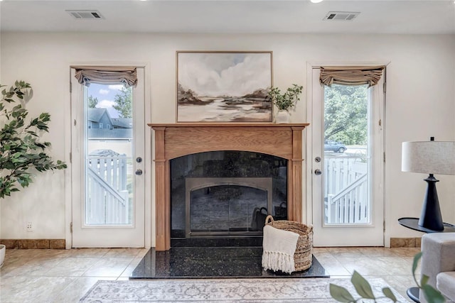 living area featuring light tile patterned floors, baseboards, a fireplace, and visible vents