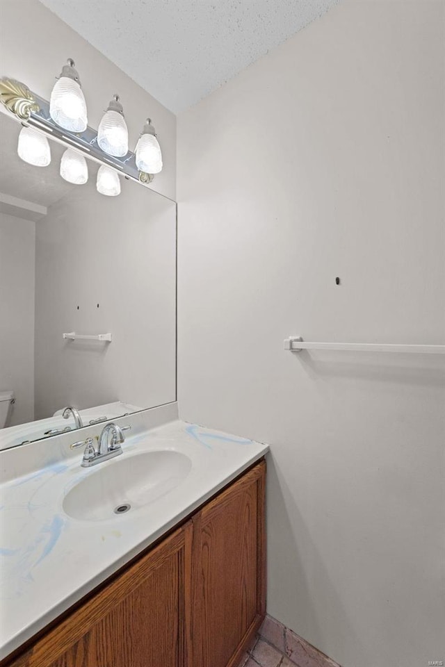 half bathroom featuring tile patterned floors, vanity, toilet, and a textured ceiling