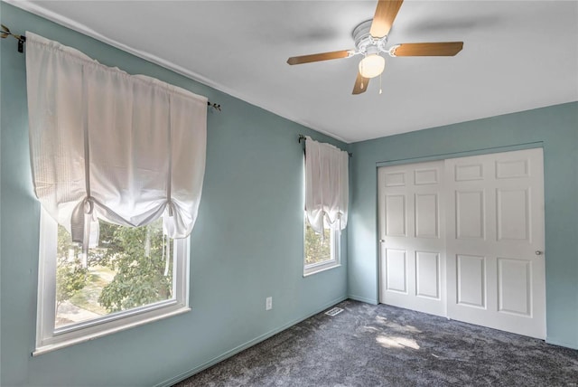 unfurnished bedroom featuring a ceiling fan, a closet, and dark carpet