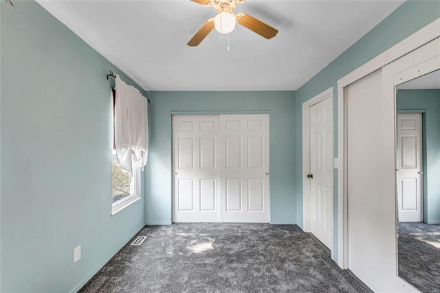 unfurnished bedroom with ceiling fan, visible vents, and dark colored carpet