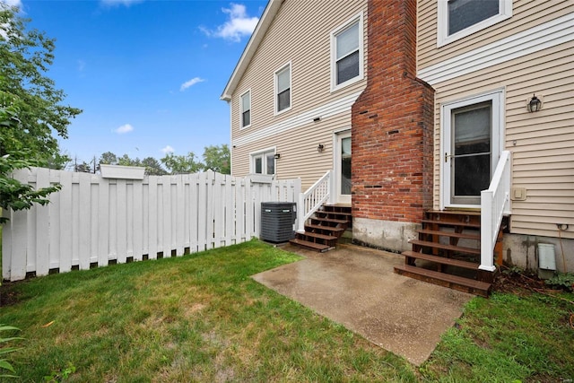 view of yard featuring entry steps, fence, and central air condition unit