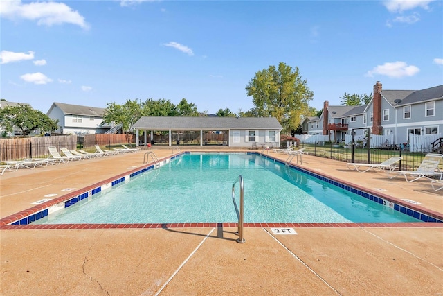 pool with a residential view, a patio area, and fence