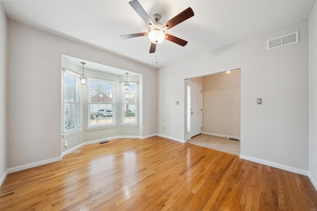 empty room with visible vents, baseboards, and light wood finished floors