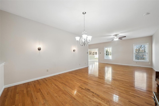 unfurnished room with ceiling fan with notable chandelier, baseboards, and light wood-style floors