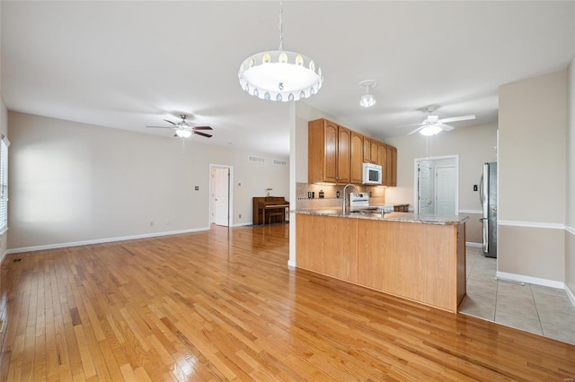 kitchen with light wood-type flooring, white appliances, a peninsula, baseboards, and ceiling fan