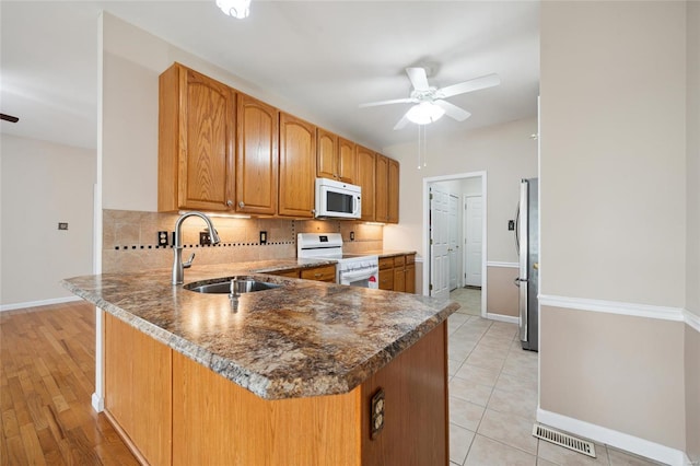 kitchen with visible vents, a ceiling fan, a sink, backsplash, and white appliances