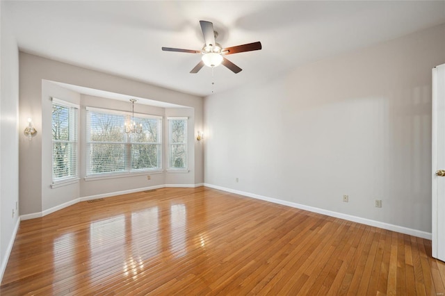 spare room with light wood-type flooring, baseboards, and ceiling fan with notable chandelier