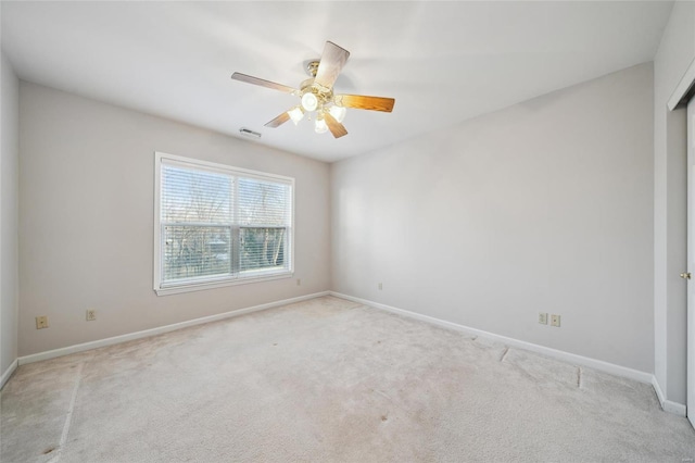 unfurnished room featuring ceiling fan, light colored carpet, visible vents, and baseboards