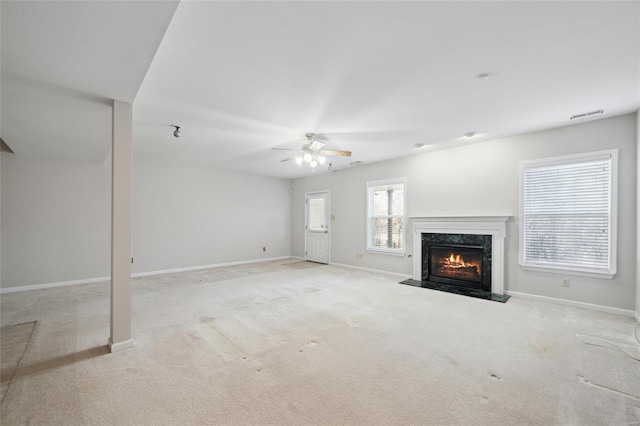 unfurnished living room featuring a high end fireplace, a ceiling fan, carpet, and baseboards