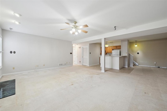 unfurnished living room with a ceiling fan, visible vents, and baseboards