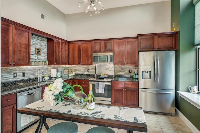 kitchen featuring tasteful backsplash, appliances with stainless steel finishes, sink, and dark stone countertops