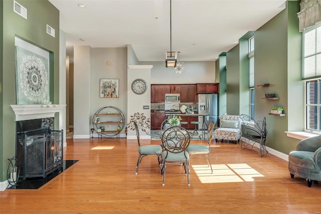 dining area with a towering ceiling and light hardwood / wood-style flooring