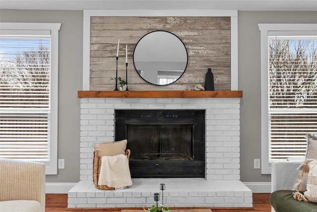 room details featuring a brick fireplace, wood finished floors, and baseboards