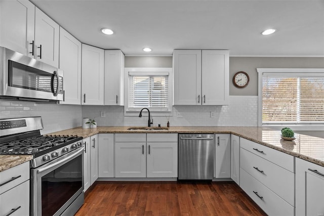 kitchen with dark wood-type flooring, light stone counters, white cabinets, stainless steel appliances, and a sink