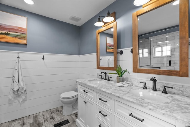 full bath with a wainscoted wall, a shower stall, toilet, and a sink