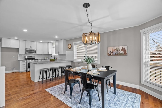 dining space with light wood-style flooring, recessed lighting, crown molding, baseboards, and a chandelier