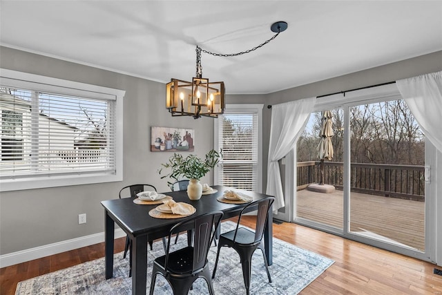 dining room with crown molding, a notable chandelier, light wood-style floors, and baseboards