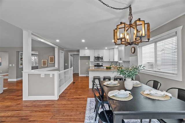 dining space with a notable chandelier, recessed lighting, baseboards, and wood finished floors