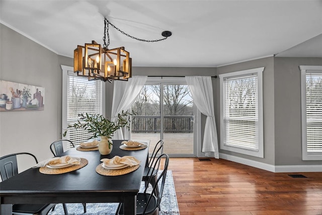 dining space featuring light wood-type flooring, plenty of natural light, baseboards, and a chandelier