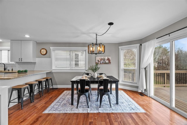 dining area with a notable chandelier, wood finished floors, visible vents, and baseboards