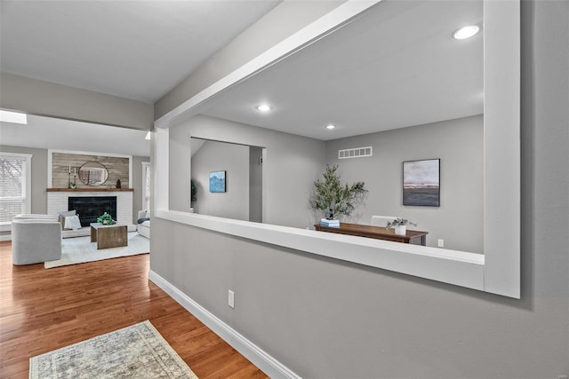 hallway with visible vents, recessed lighting, baseboards, and wood finished floors