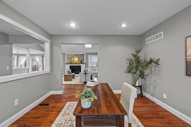 office with visible vents, a large fireplace, and wood finished floors