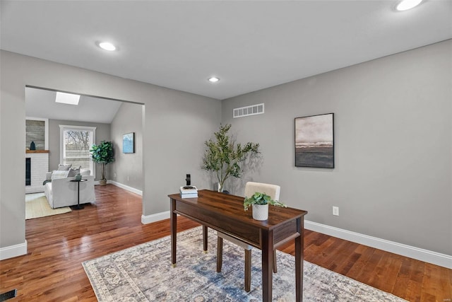 home office with visible vents, baseboards, recessed lighting, a fireplace, and wood finished floors