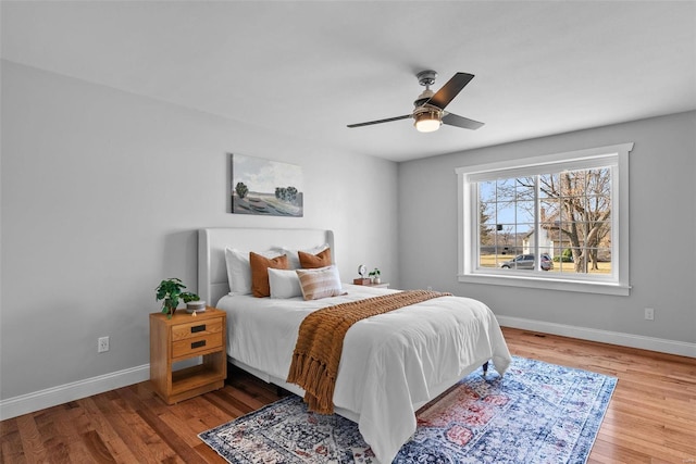 bedroom with ceiling fan, baseboards, and wood finished floors