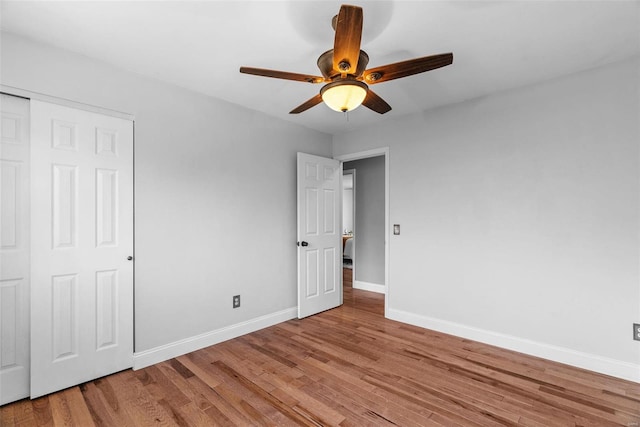 unfurnished bedroom with a closet, light wood-style flooring, baseboards, and ceiling fan