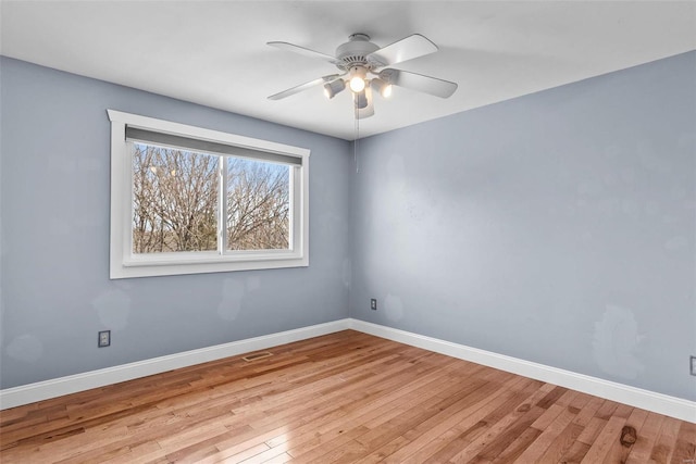 spare room with hardwood / wood-style flooring, a ceiling fan, and baseboards