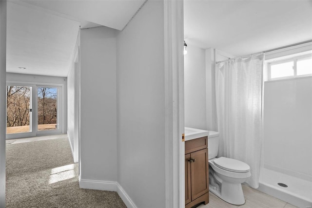 full bath featuring vanity, toilet, baseboards, and a stall shower