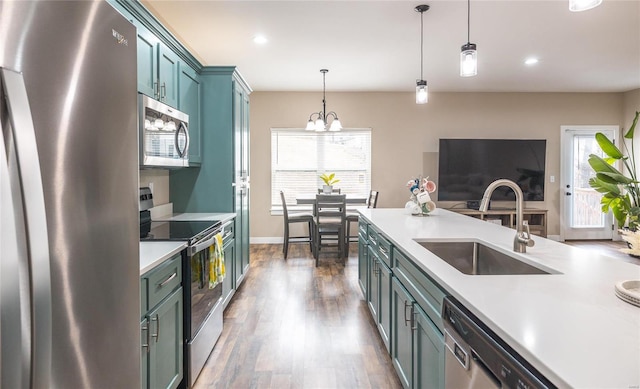 kitchen with dark wood-type flooring, decorative light fixtures, stainless steel appliances, light countertops, and a sink